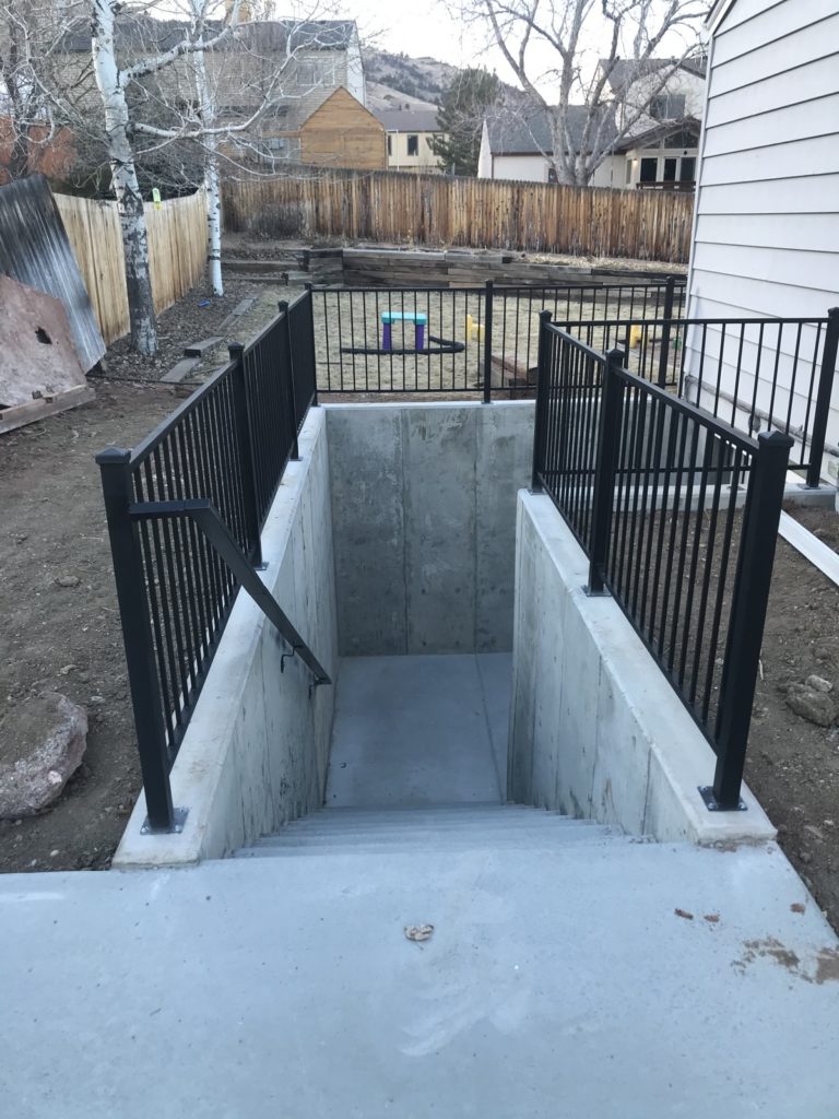 Concrete walkout basement stairwell leading to a basement door