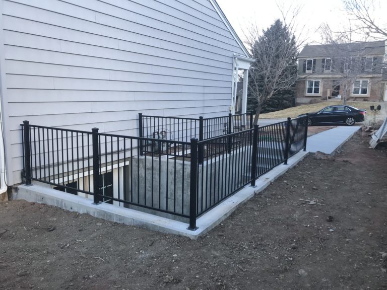 Concrete walkout basement stairwell with black metal railing