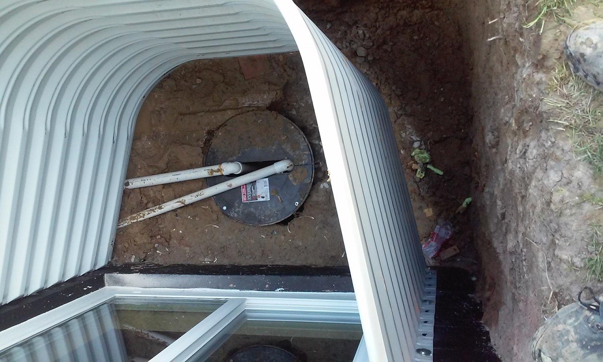 Sump pump and discharge pipe installed in a basement window well