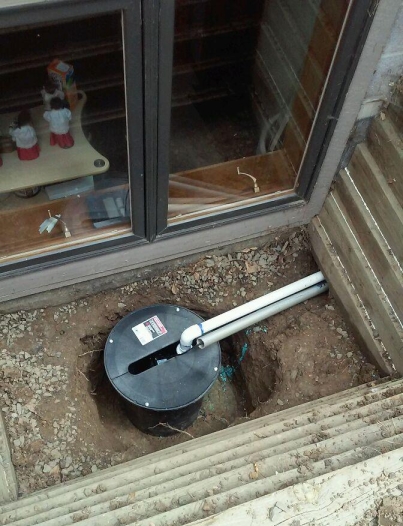 Window well sump pump being installed below the gravel