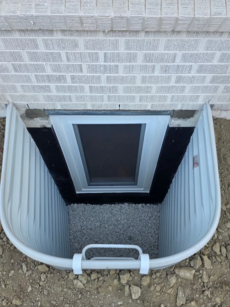 Galvanized window well with ladder and gravel base outside a new basement window in Boulder, CO.
