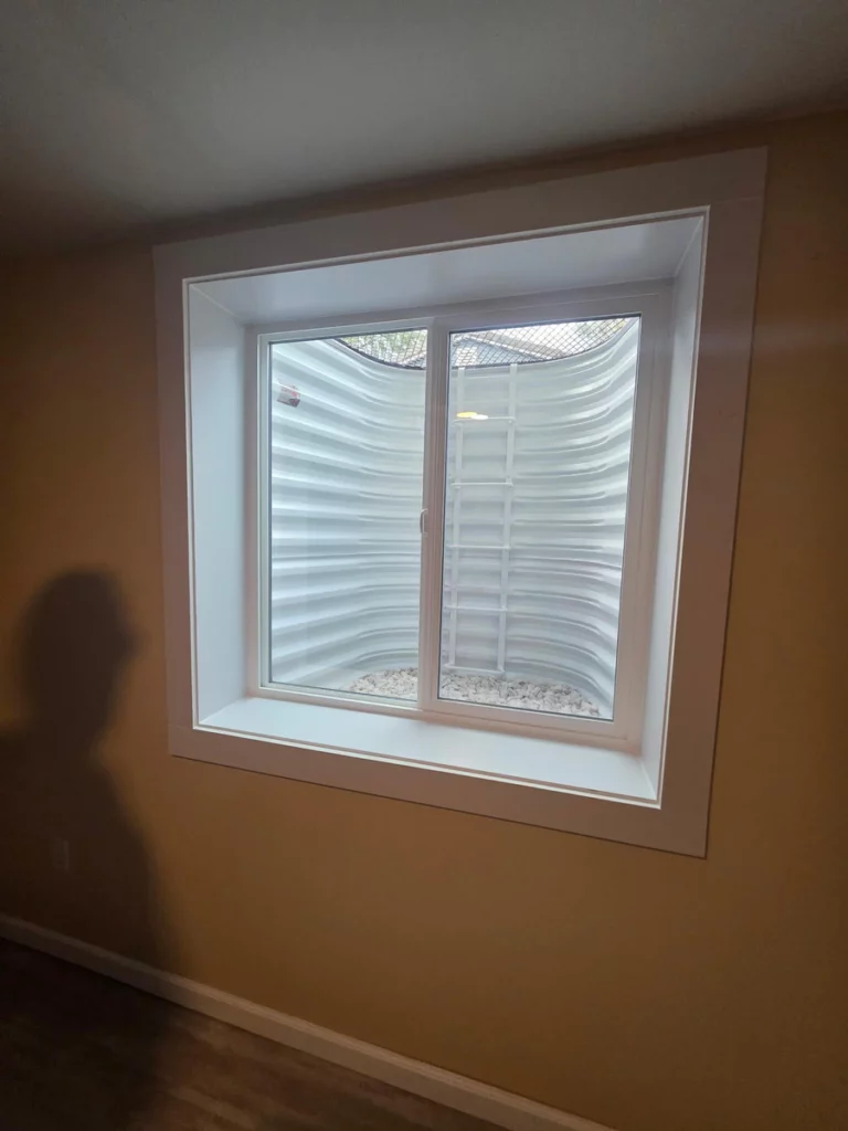White slider egress window with extension jambs and casing in a finished basement room in Denver, CO.